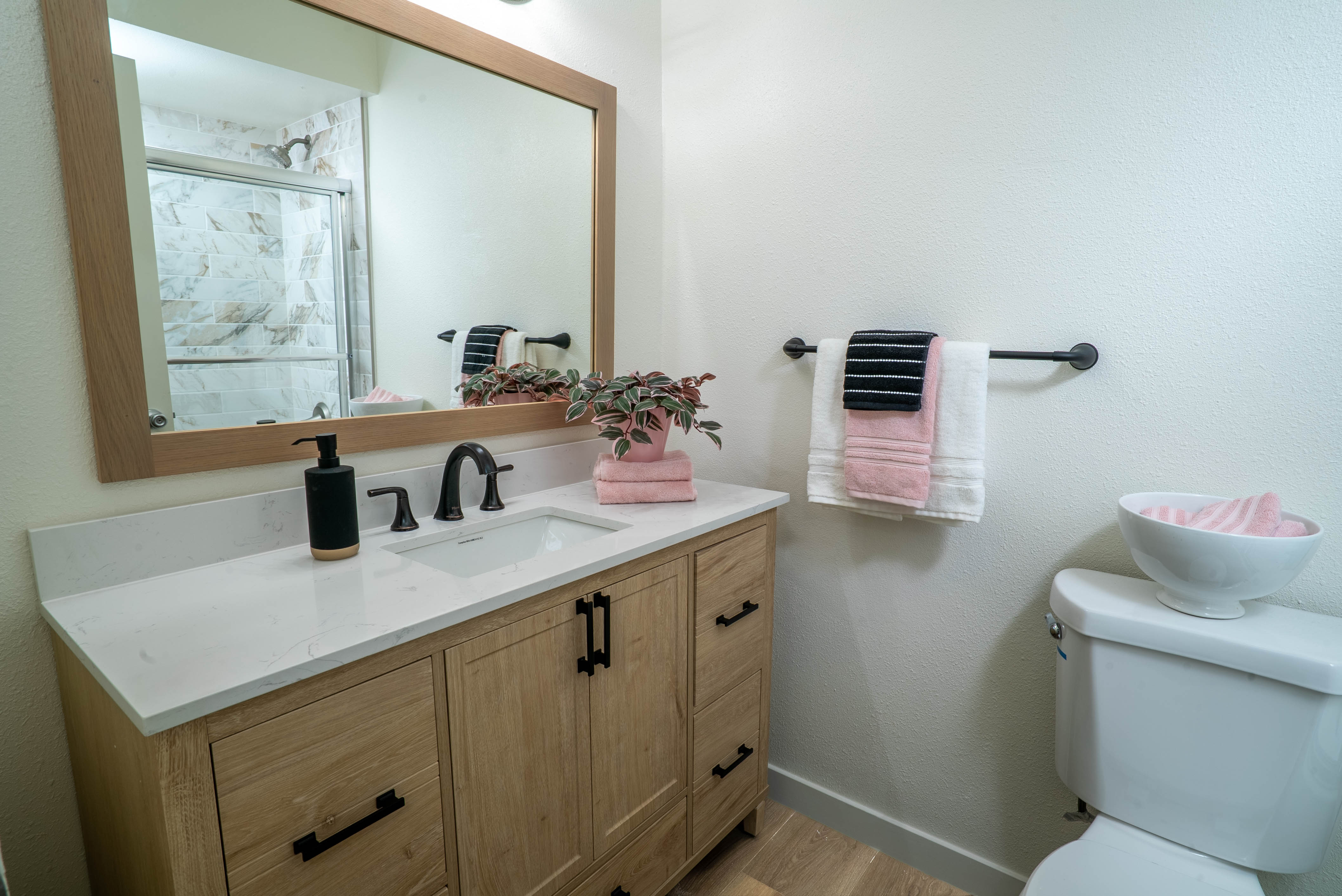 Bathroom vanity with wood cabinetry and framed mirror