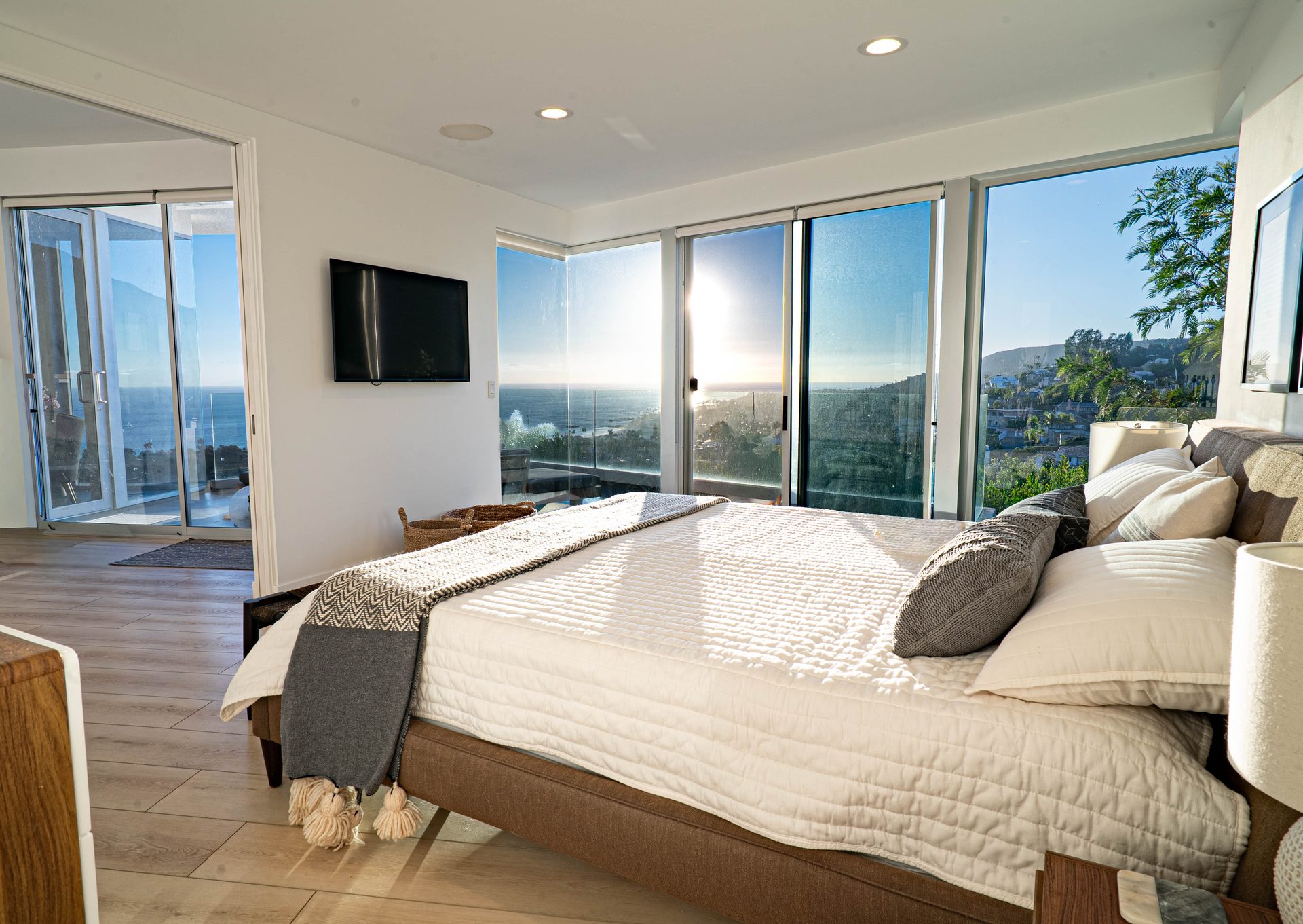Primary bedroom with wall-mounted TV and coastline view at sunrise