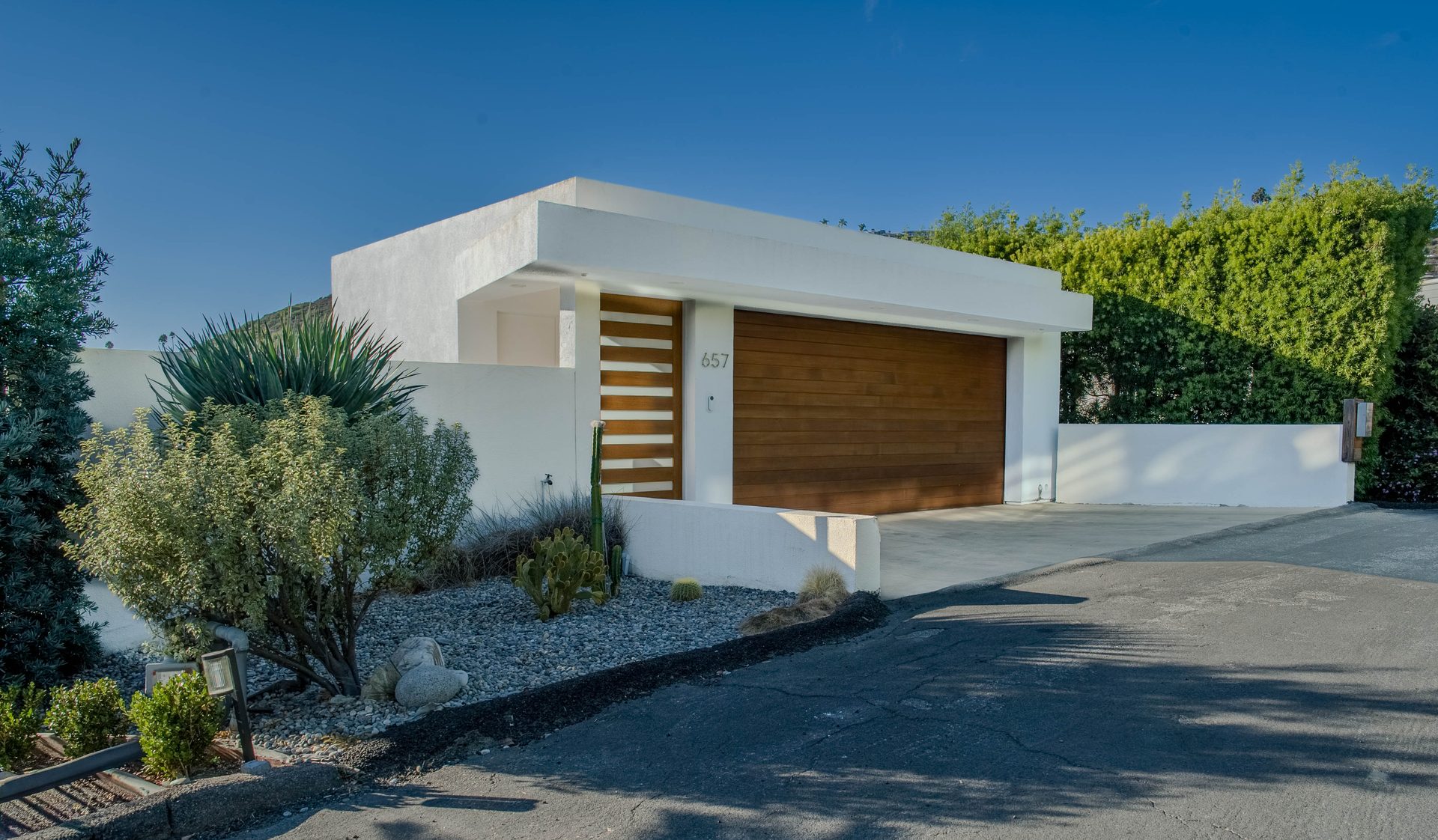 Mid-century modern front exterior with wood garage door and desert landscaping
