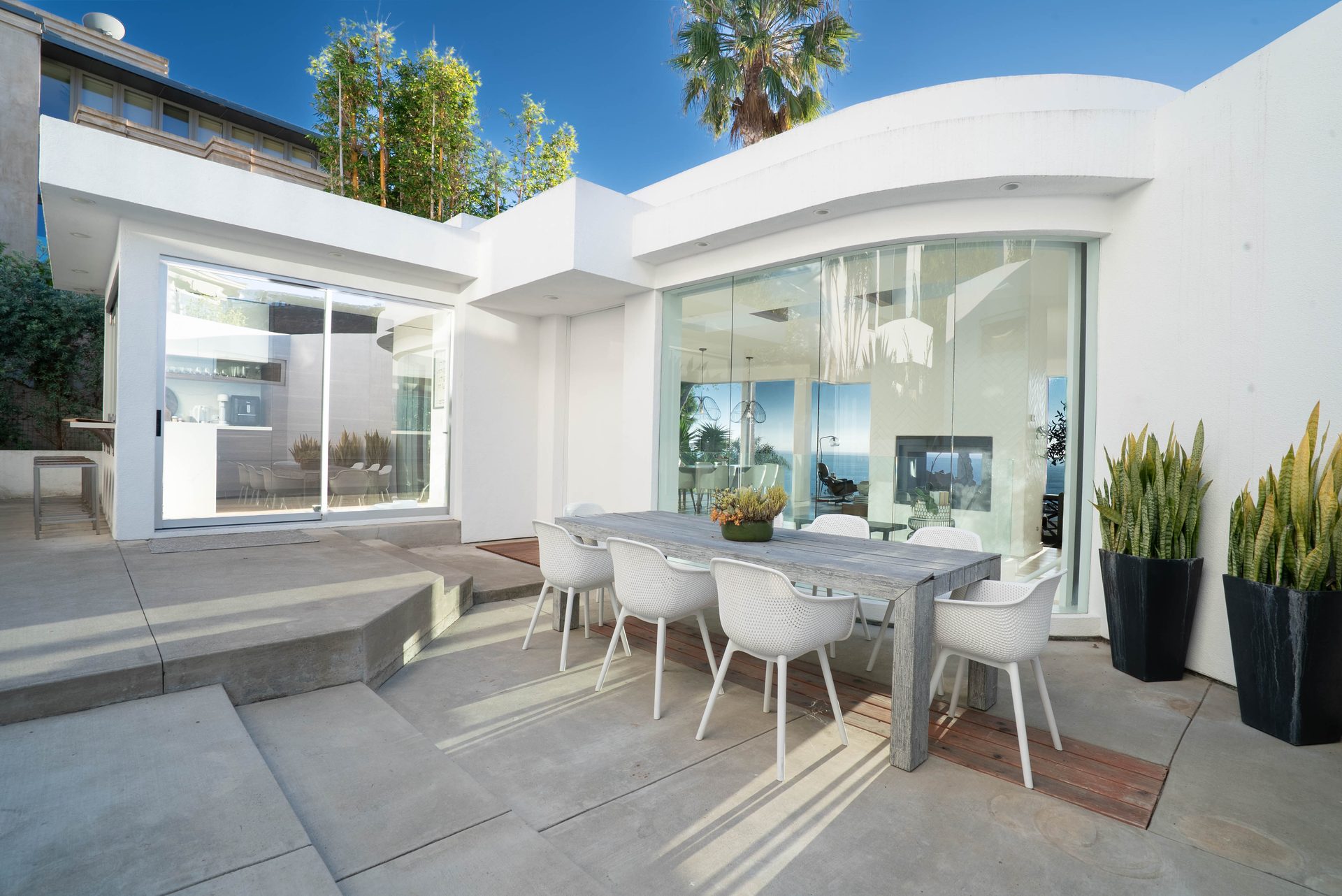 Outdoor patio with dining table and ocean-view glass walls