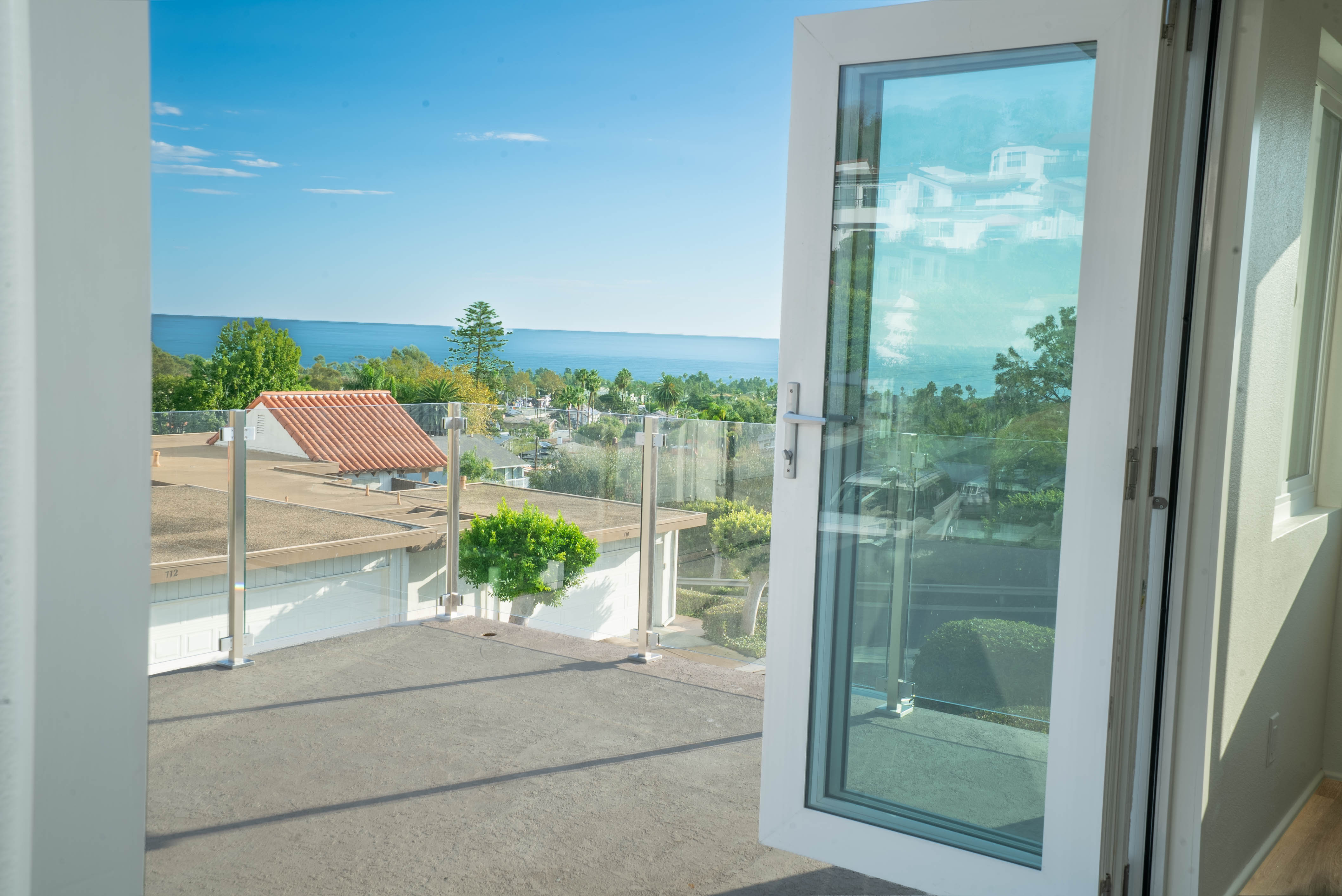 Open glass door looking out to a rooftop deck and coastline view